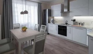 Contemporary kitchen featuring luxury vinyl flooring with white cabinets and light grey kitchen table and chairs